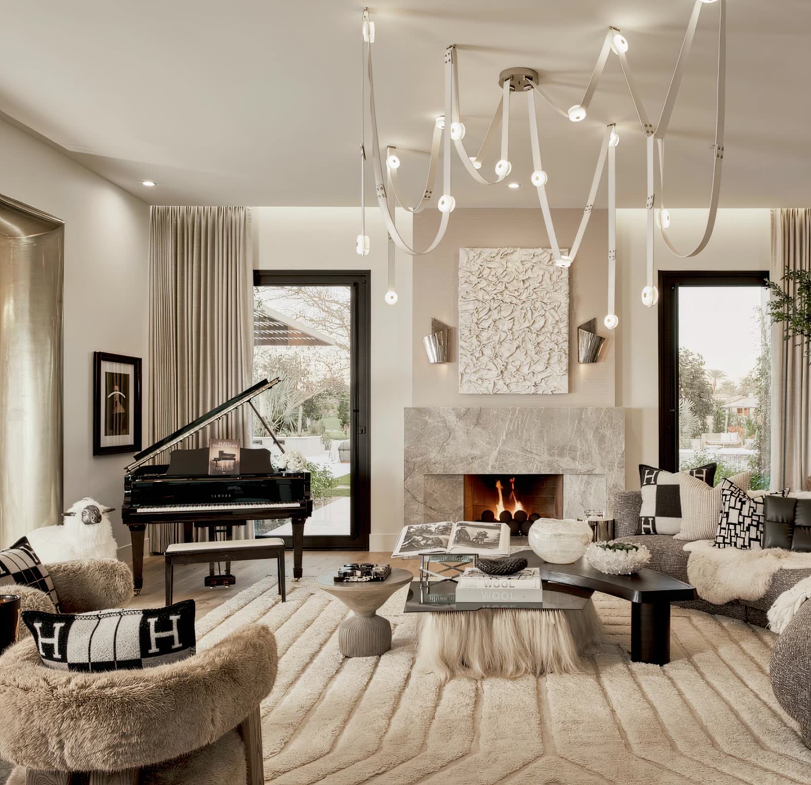 Finished living room with grand piano, sculptural chandelier and layered creams